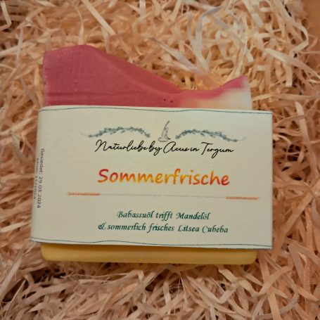 Eine Seife liegt auf einer Holzwolleunterlage mit Aufschrift Sommerfrische